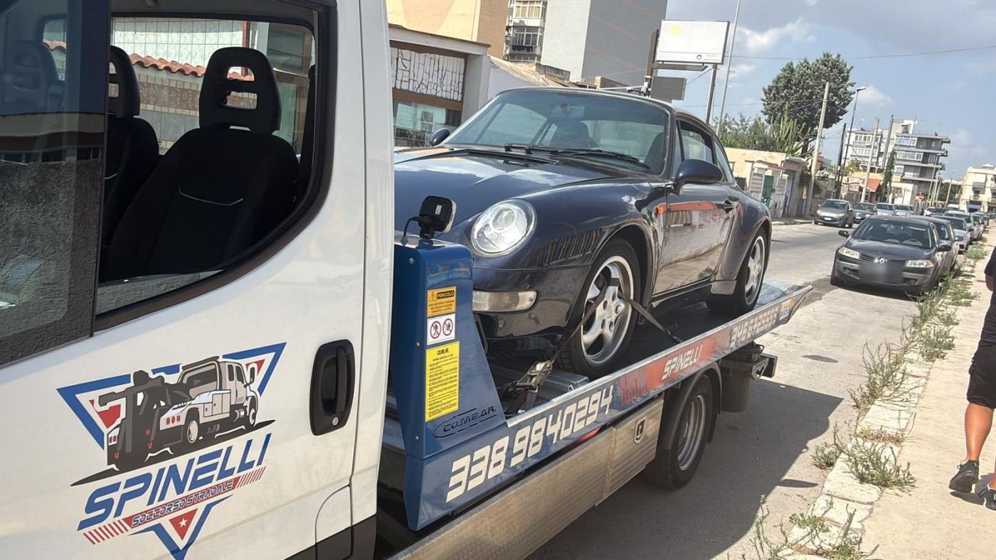 Porsche 911 sul pianale, con lo stemma Spinelli sulla porta del carro attrezzi